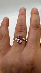 14k yellow gold ring with pink oval sapphire on hand, angled view