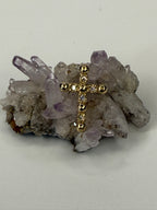 14k yellow gold diamond cross on gray rock with purple crystal points