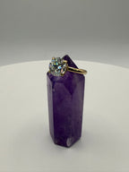 Yellow gold solitaire ring with round halo-set center stone on display