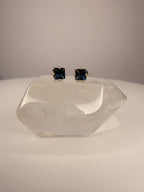 Square blue sapphire stud earrings in yellow gold with four-prong settings.