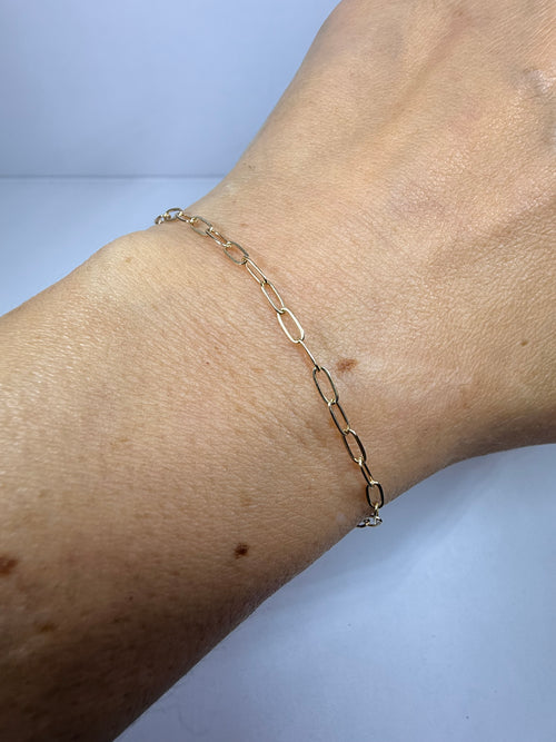 Model wearing a 10k solid yellow gold 7 inch paperclip link bracelet on wrist