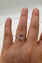 14k yellow gold ring with pink oval sapphire on hand, front view