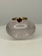 14k yellow gold garnet ring on display vase, round dark red center stone