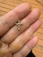 Gold cross pendant with small round diamond accents, held on open palm