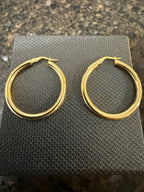 14k yellow gold round hoop earrings flat on textured black display