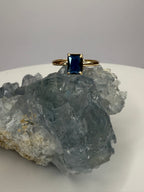 14k yellow gold sapphire ring with emerald-cut dark blue stone, four prongs visible