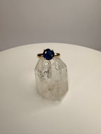 14k yellow gold ring with round dark blue sapphire on faceted crystal display