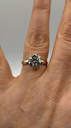 14k yellow gold engagement ring with round moissanite center stone on finger