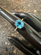 Oval blue topaz gemstone on 10k yellow gold ring, prongs visible in close-up