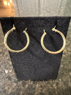 Gold hoop earrings on a black earring stand.