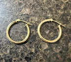 Gold hoop earrings on a textured surface