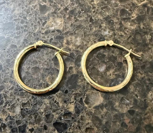 Gold hoop earrings on a textured surface