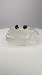 Yellow gold princess-cut sapphire studs with square blue stones and four-prong settings.
