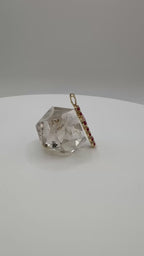 Gold ring with a diamond on a clear stone stand against a gray background