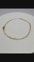 Close up detail of 10k yellow gold 2.1mm paperclip links showing high polish finish and lobster clasp